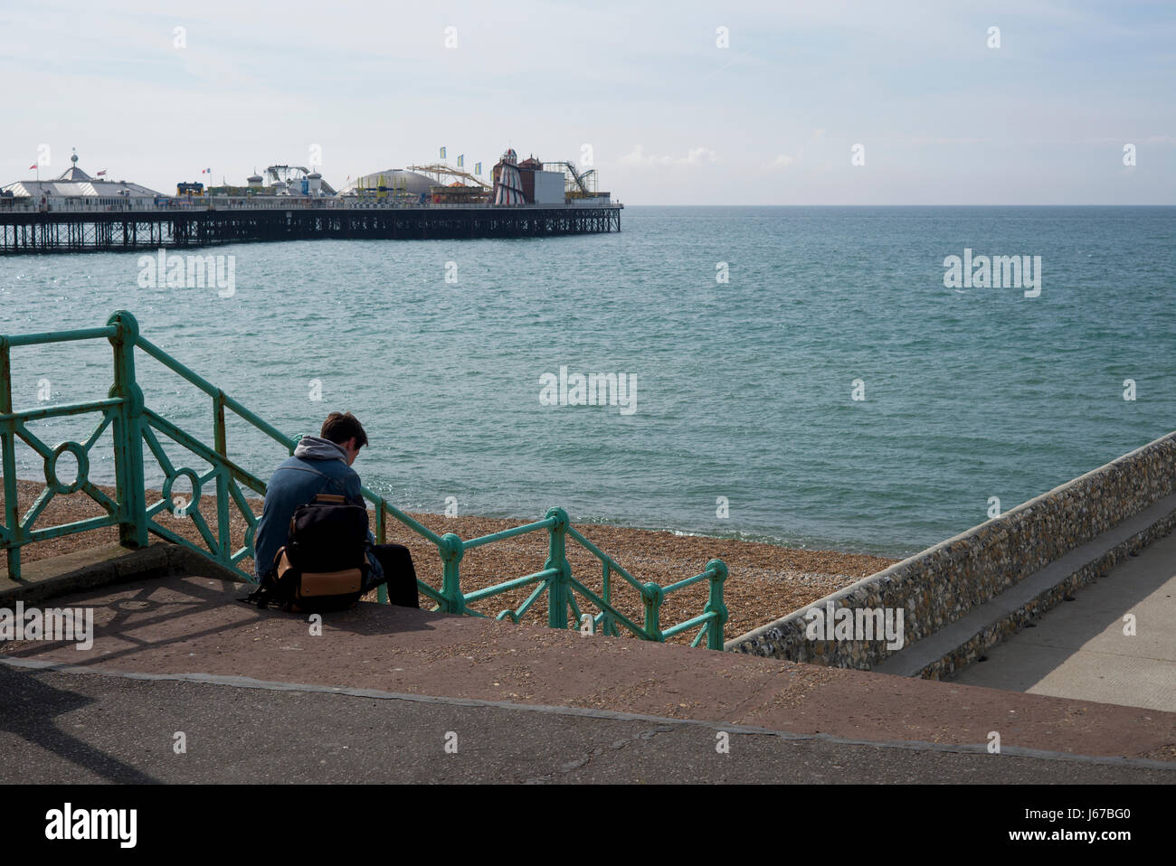 Jeune homme phone sur étapes menant à la plage, Brighton, UK Banque D'Images