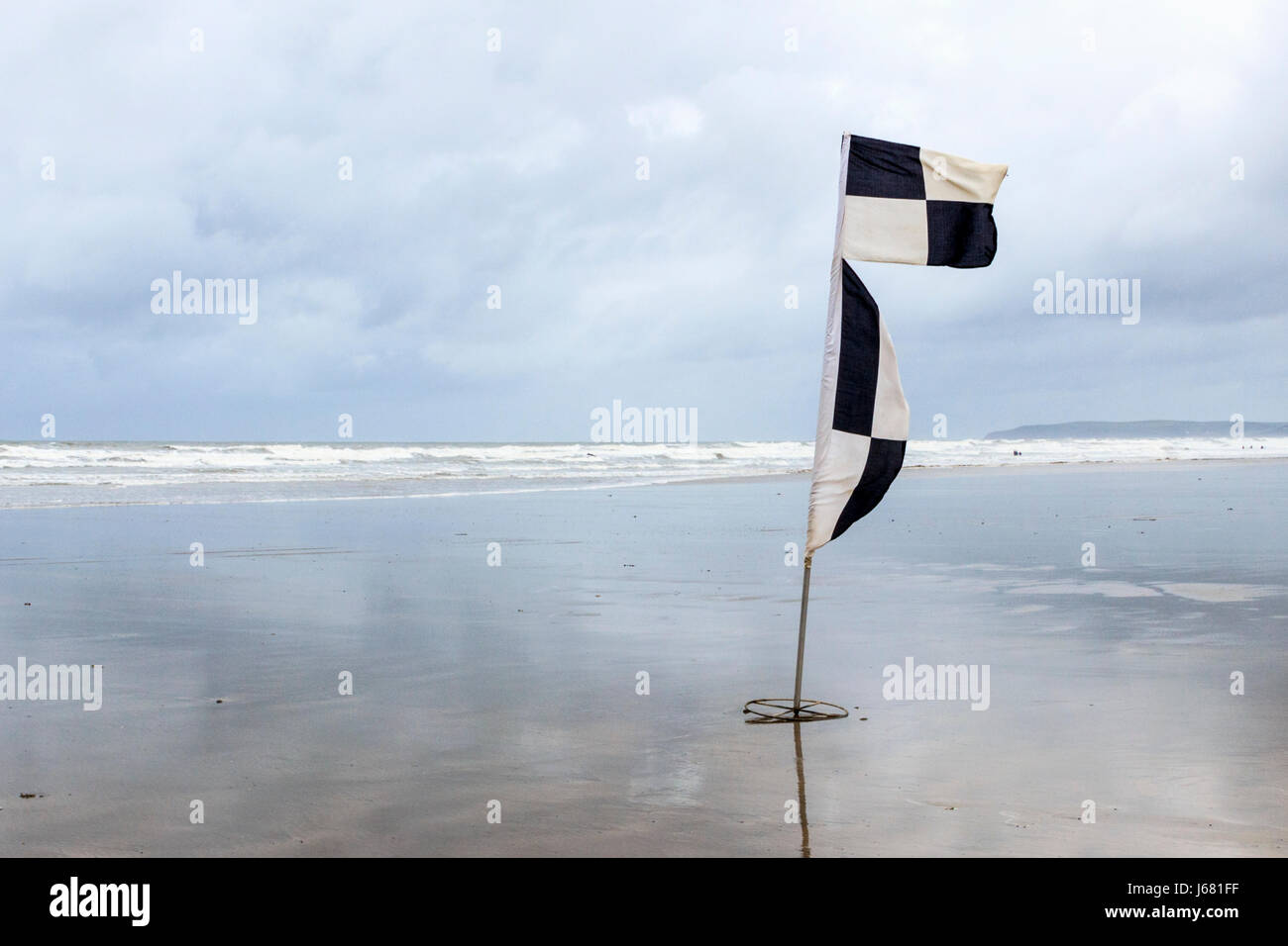 Un avertissement en damier noir et blanc drapeau sur la plage de sable déserte à Westward Ho !, Devon, UK Banque D'Images