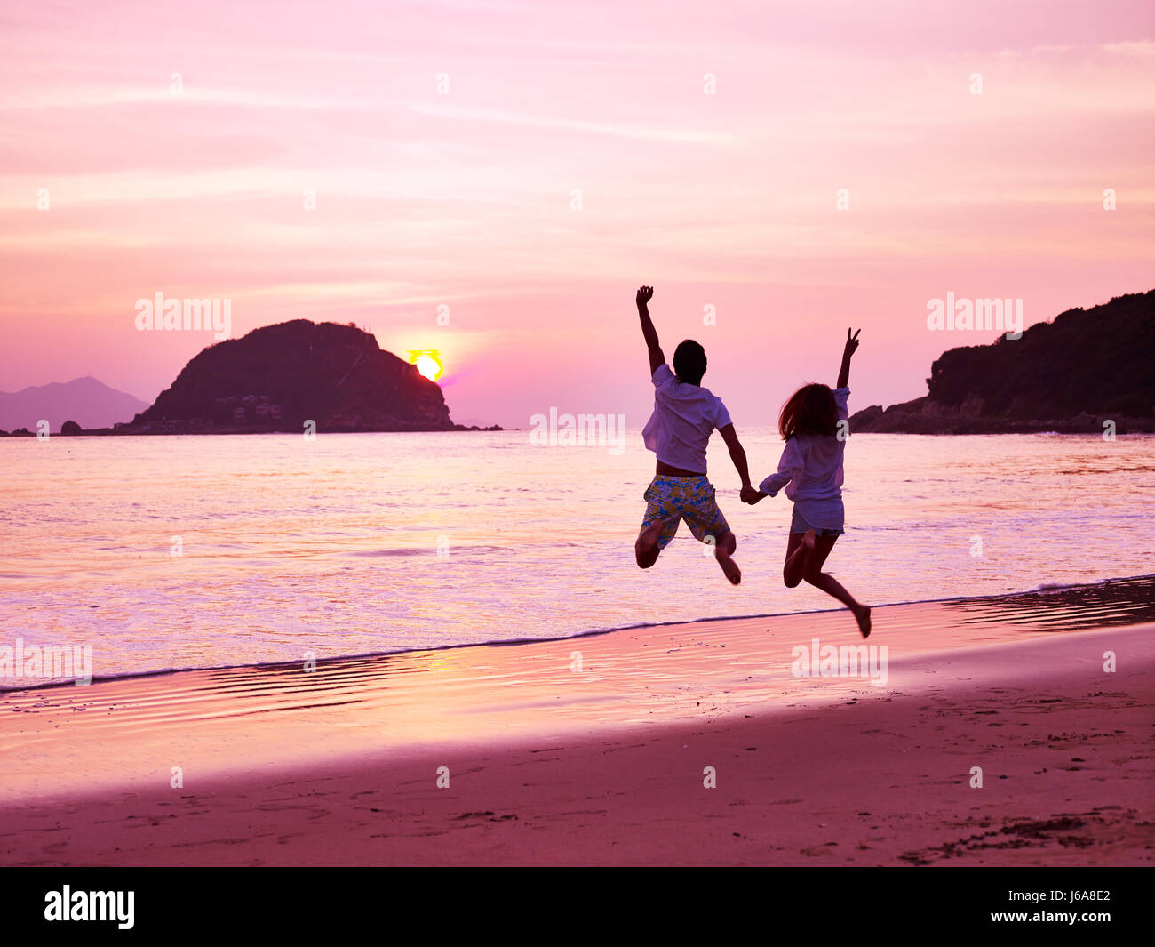 Young Asian Woman cheering et de joie sur la plage, le soleil se lever. Banque D'Images