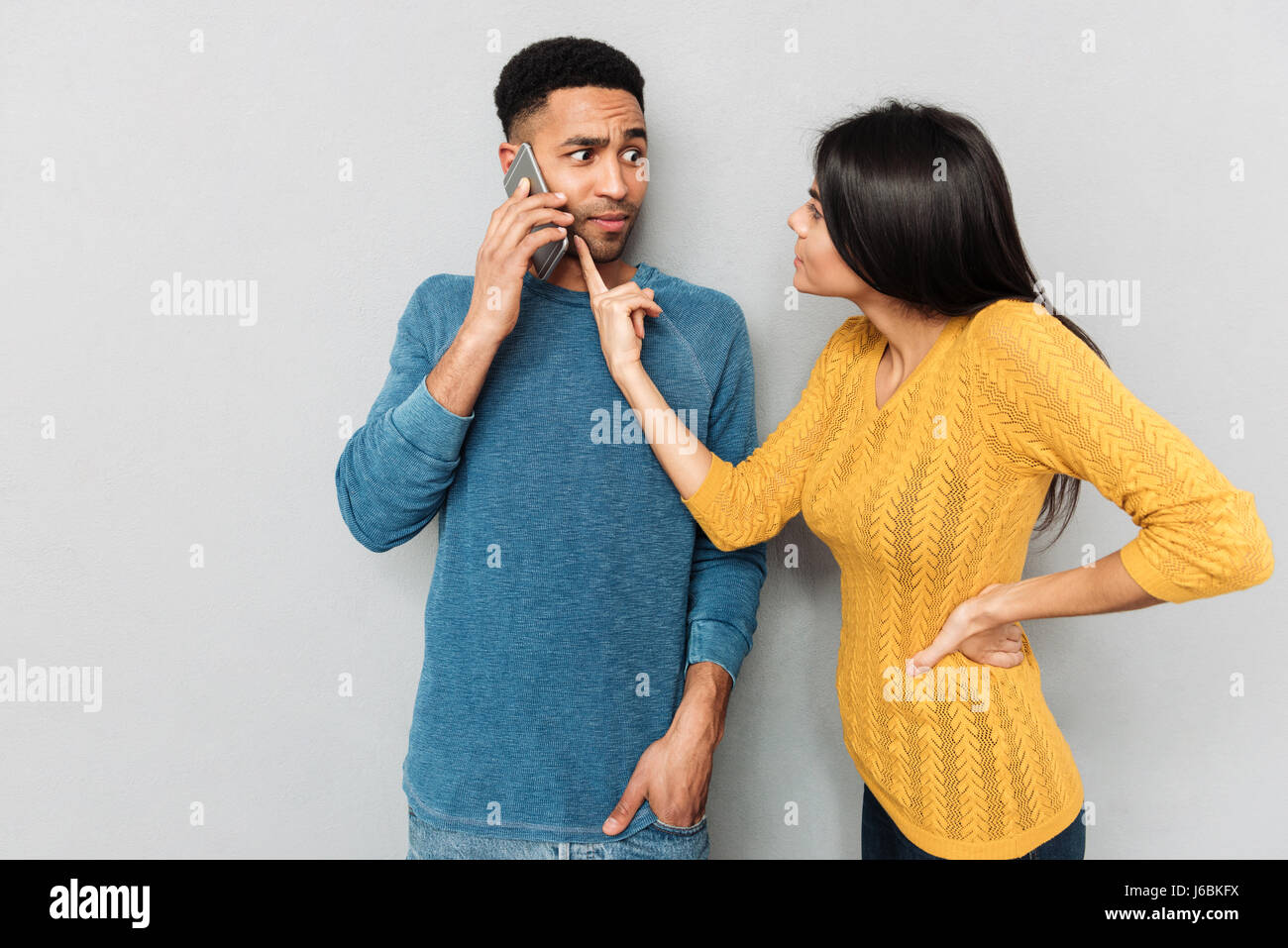 Déplut woman pointing at téléphone de son mari avec la revendication isolée Banque D'Images
