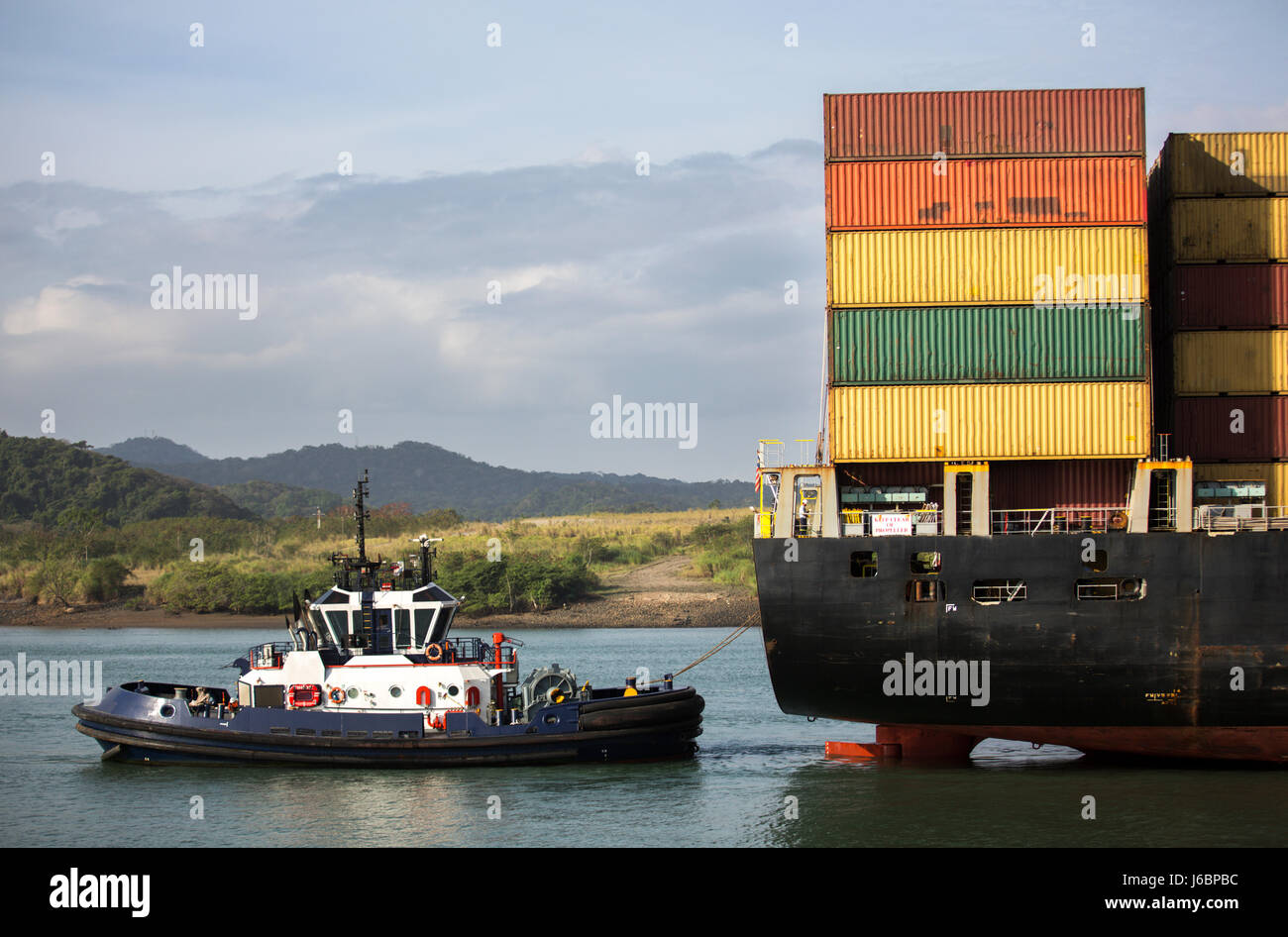 Porte-conteneurs qui est poussé par un remorqueur dans le canal de Panama Banque D'Images