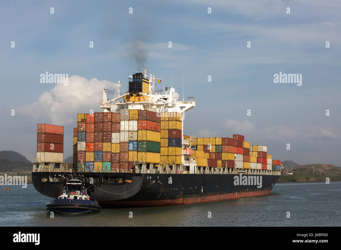 Porte-conteneurs qui est poussé par un remorqueur dans le canal de Panama Banque D'Images