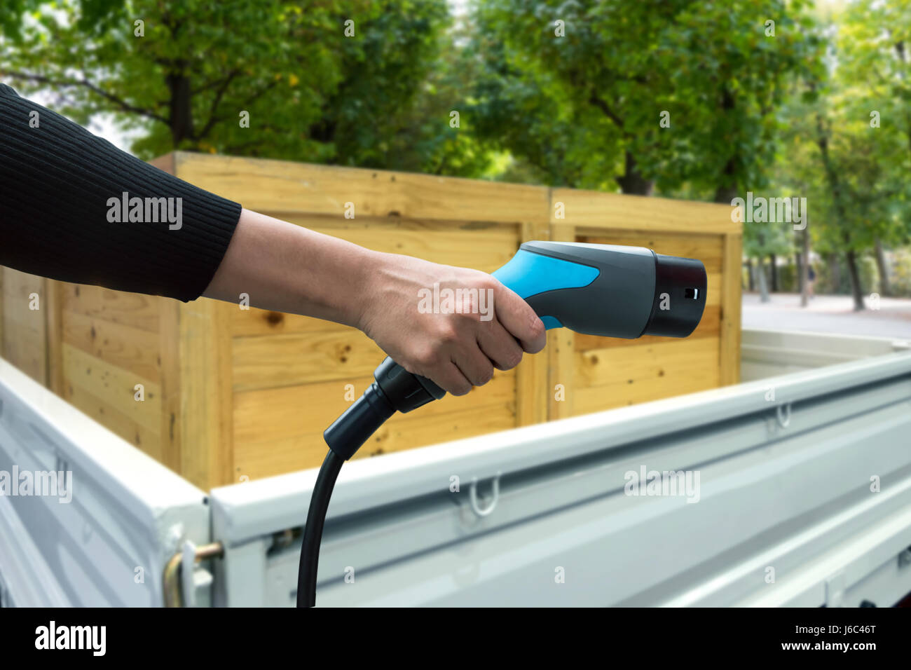 La pollution de l'air et réduire les émissions de gaz à effet de serre. Main tenant et de charge de voiture électrique voiture camion logistique et vert nature voir zone Banque D'Images