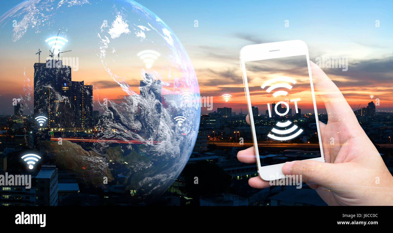 Internet des objets , iot , smart home , des ville et réseau connexion concept. Human hand holding blanc téléphone et l'icône de l'ito avec coucher de soleil et la ville Banque D'Images