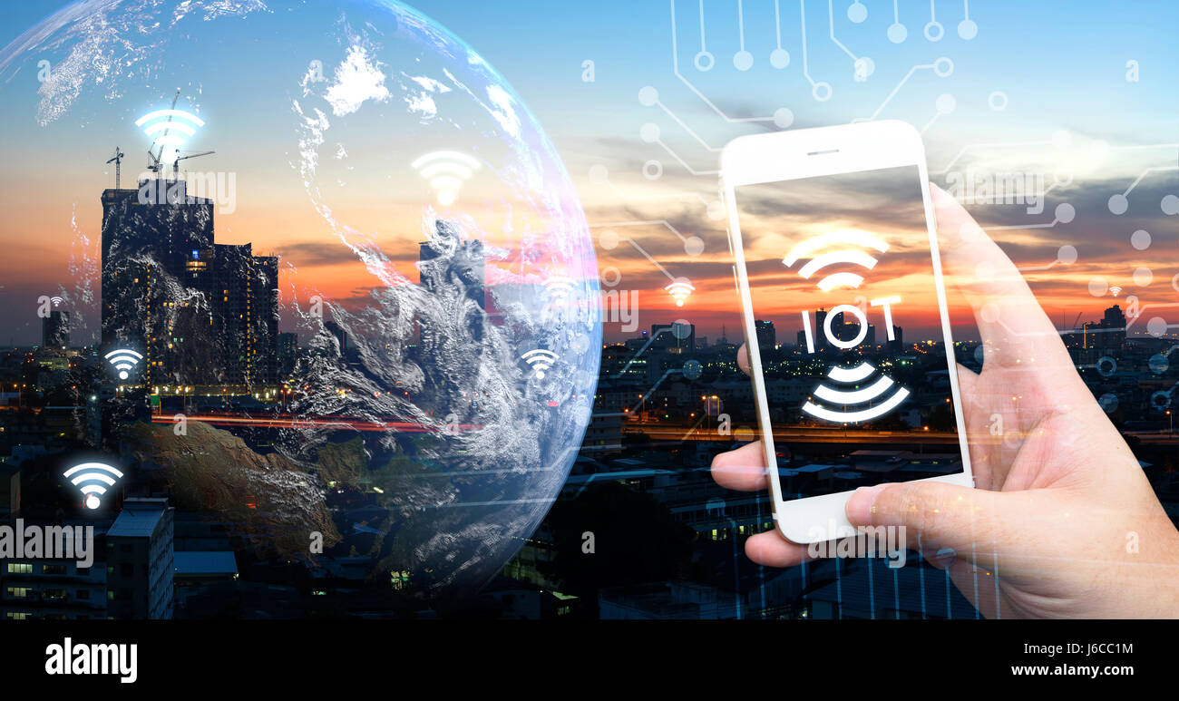 Internet des objets , iot , smart home , des ville et réseau connexion concept. Human hand holding blanc téléphone et l'icône de l'ito avec coucher de soleil et la ville Banque D'Images