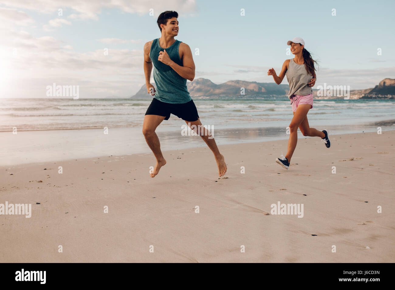 Shot de couple remise en forme d'exécution sur la plage. Heureux jeune homme et femme porteur au bord de la mer. Banque D'Images