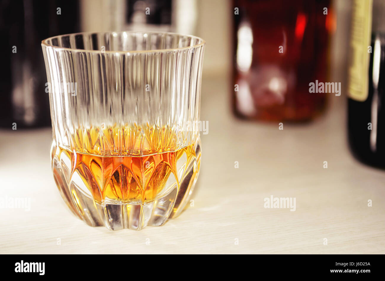 Le verre cristal avec une dose de whisky pur, pas de glace, avec un  arrière-plan flou d'une bouteille de whisky Photo Stock - Alamy