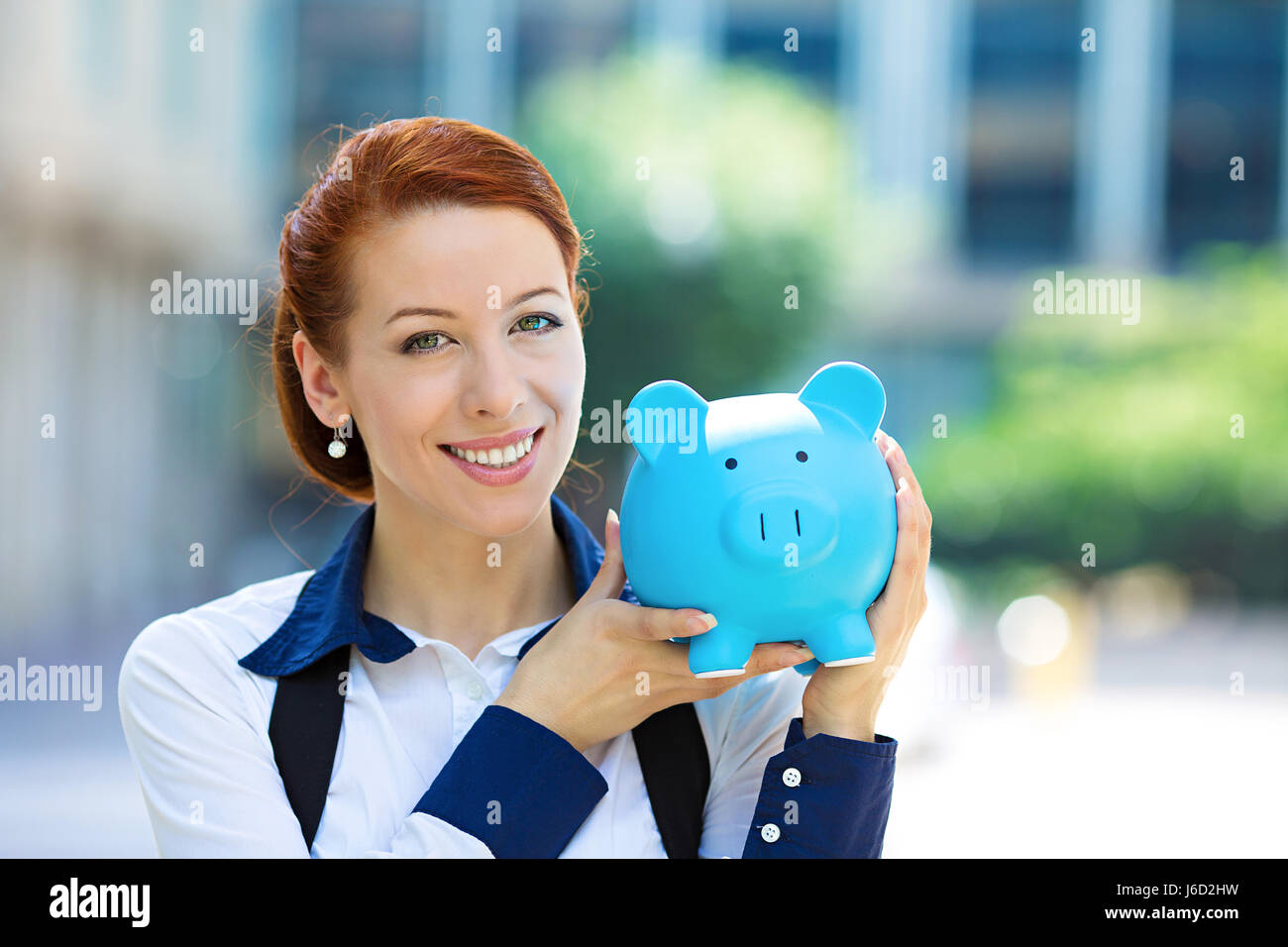 Closeup portrait heureux, smiling business woman, employé de la banque holding piggy bank, isolé à l'extérieur du bureau d'arrière-plan. Les économies financières, ba Banque D'Images