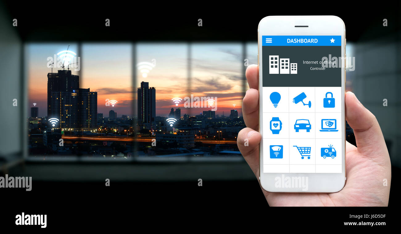 Internet des objets , iot , smart home , des ville et réseau connexion concept. Human hand holding blanc téléphone et l'application avec city sunset view b Banque D'Images