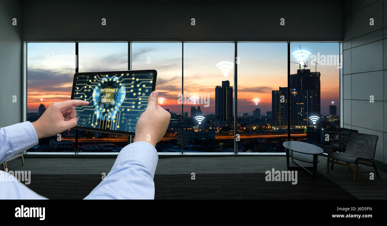 Internet des objets , l'Ito et réseau connexion concept. Businessman hand holding tablet noir avec city sunset , wifi icones et stock technique graphique ba Banque D'Images