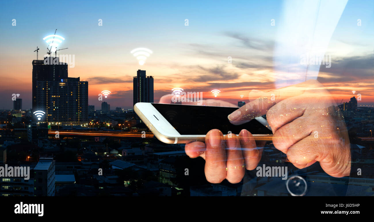 Internet des objets , Réseau , ito concept. Femme d'affaires à pointer du doigt l'écran noir téléphone mobile avec bâtiment Bâtiment de ville metropolis bac coucher du soleil Banque D'Images