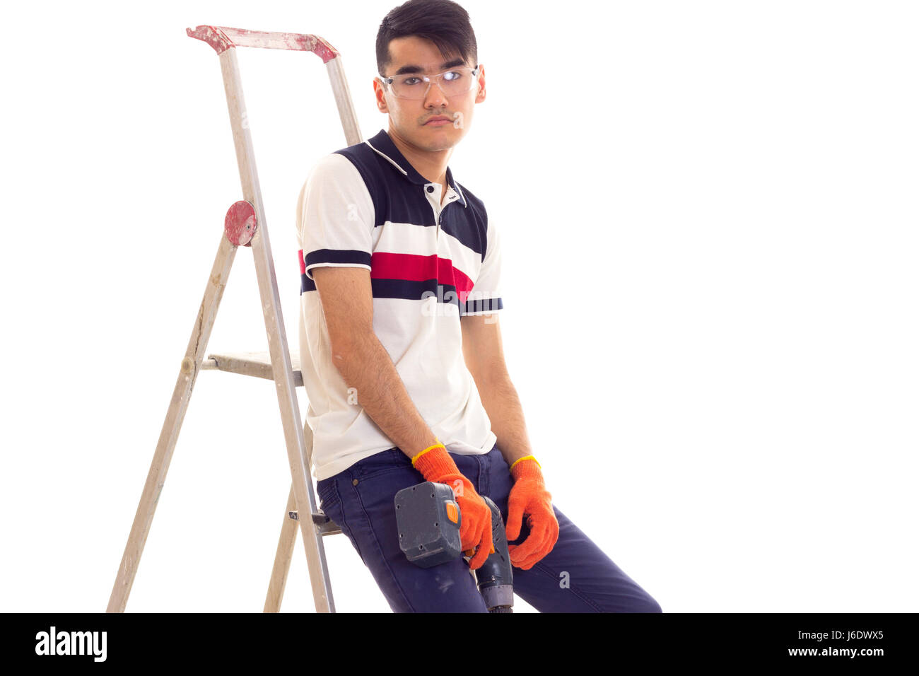 Young man holding tournevis électrique et assis sur ledder Banque D'Images
