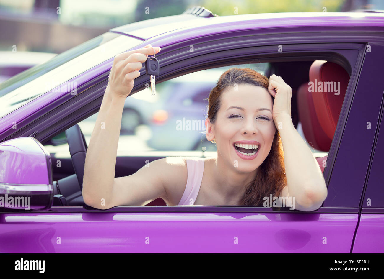 Closeup portrait heureux, souriant, jeune femme séduisante, l'acheteur s'asseoir dans sa nouvelle voiture mauve clés montrant l'extérieur isolé, du concessionnaire concessionnaire offi lot Banque D'Images