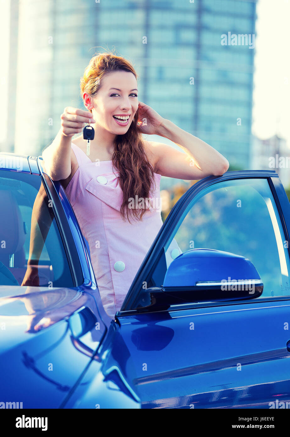 Portrait of happy smiling young attractive woman acheteur debout à côté de nouvelle voiture bleue clés montrant l'extérieur isolé, concessionnaire de l'entreprise concessionnaire lot offic Banque D'Images