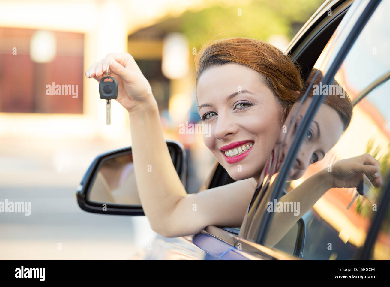 Closeup portrait heureux, souriant, jeune femme séduisante, l'acheteur s'asseoir dans sa nouvelle voiture bleue montrant l'extérieur, isolé des clés concessionnaire concessionnaire lot, offic Banque D'Images