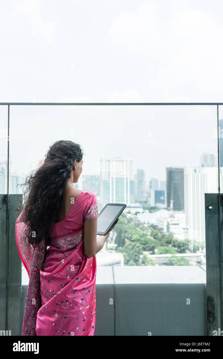 Jeune femme indienne à l'aide d'un tablet PC sur une terrasse dans un jour de vent Banque D'Images