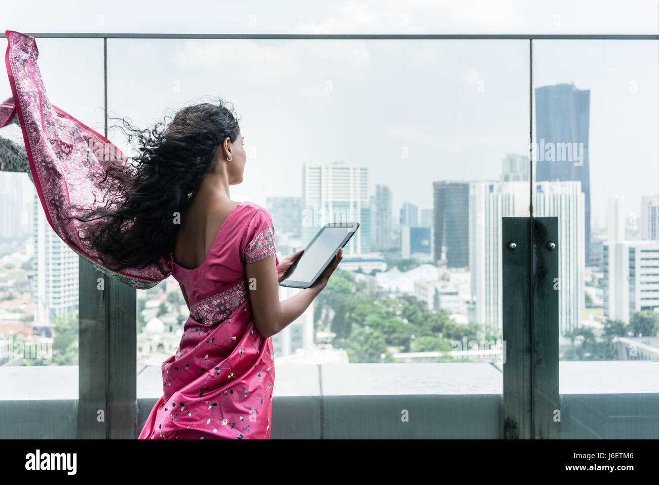 Jeune femme indienne à l'aide d'un tablet PC sur une terrasse dans un jour de vent Banque D'Images