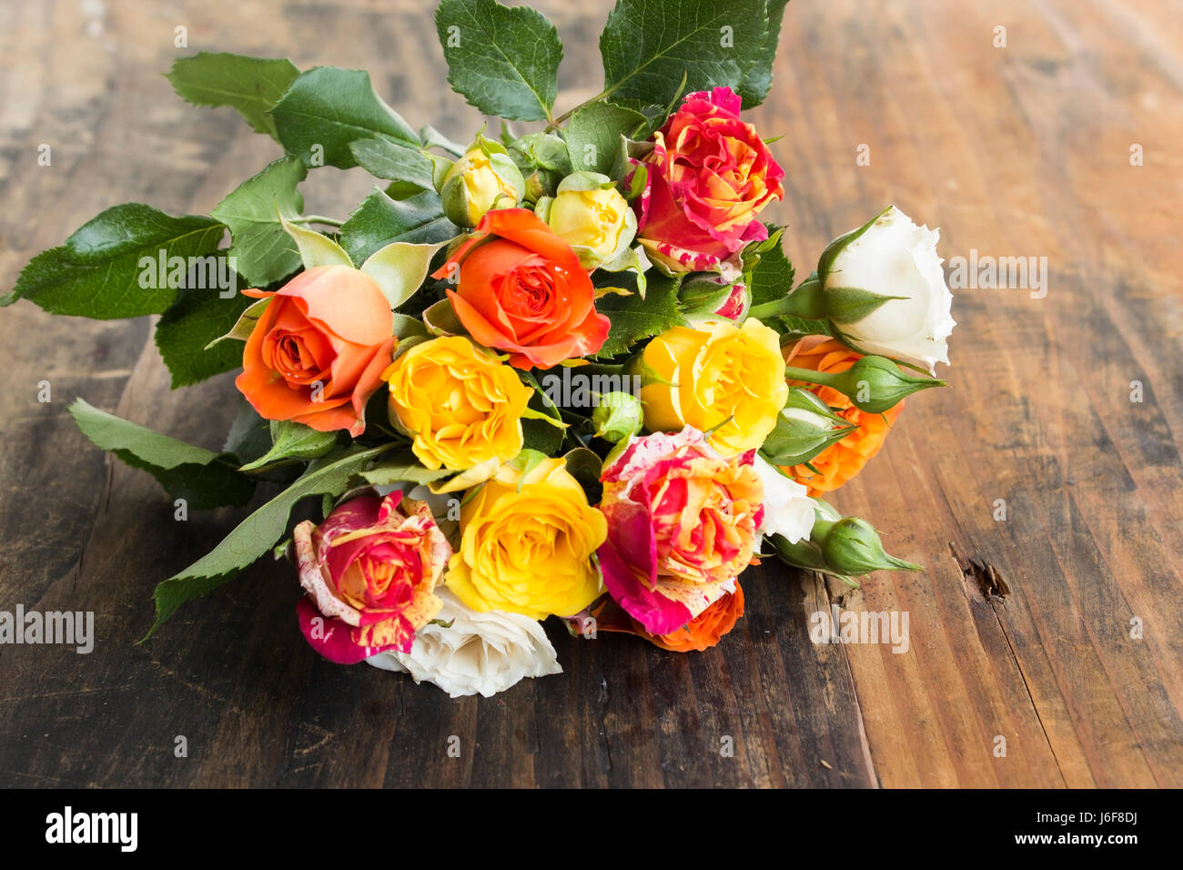 Bouquet de roses multicolores sur un fond, rustique en bois. Banque D'Images