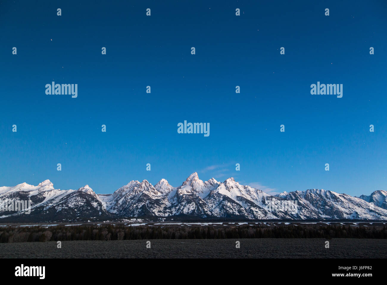 Le Teton Mountains allumé avec pré-aube lumière au-dessous d'une décoloration du ciel nocturne. Parc National de Grand Teton, Wyoming Banque D'Images