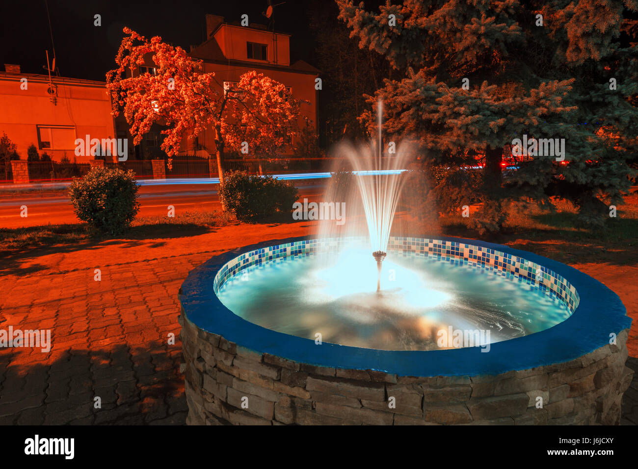 Petite fontaine dans la ville de nuit. La rue Rouge la lumière et l'eau qui coule Banque D'Images