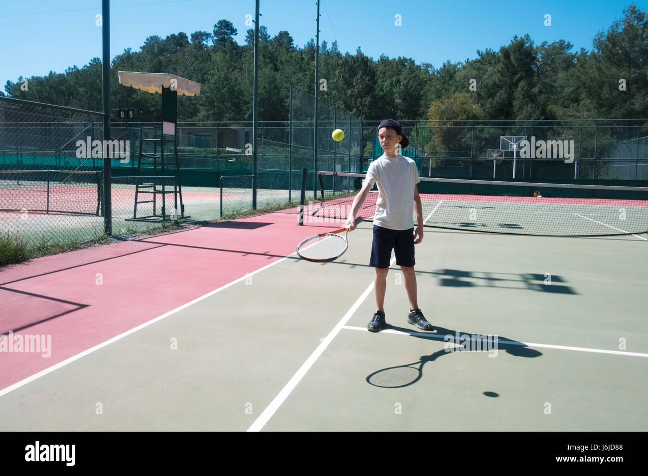Garçon avec la raquette sur un court de tennis. Journée ensoleillée en été Banque D'Images