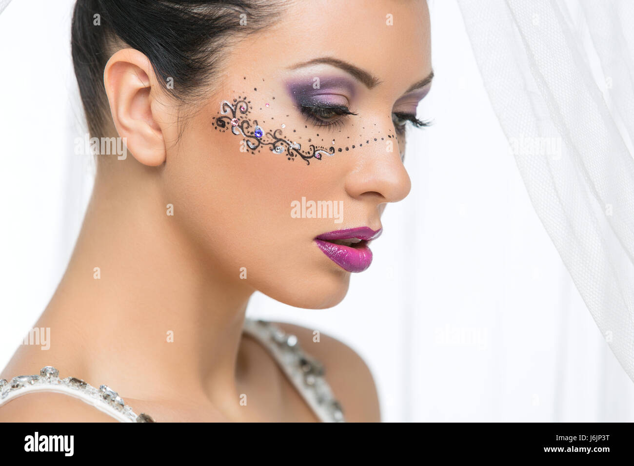 Belle jeune femme en robe de mariage avec le maquillage et masque dessiné  autour des yeux. Mariée avec le grand arc blanc sur la tête. Gros plan de  tir Photo Stock -