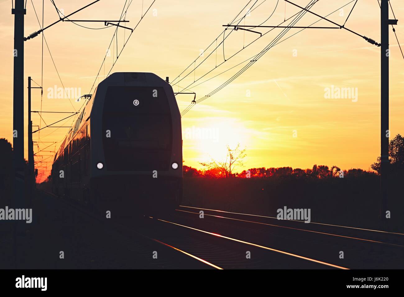 Silhouette du train de voyageurs modernes. Chemin de fer au beau coucher du soleil (heure d'or). Banque D'Images