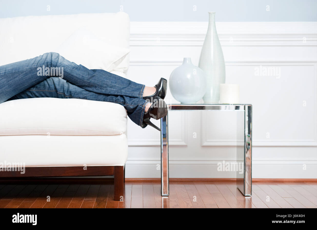 Femme jambes chambre bleu Jeans Pantalons Pantalon jean femme accueil table table jambes Banque D'Images