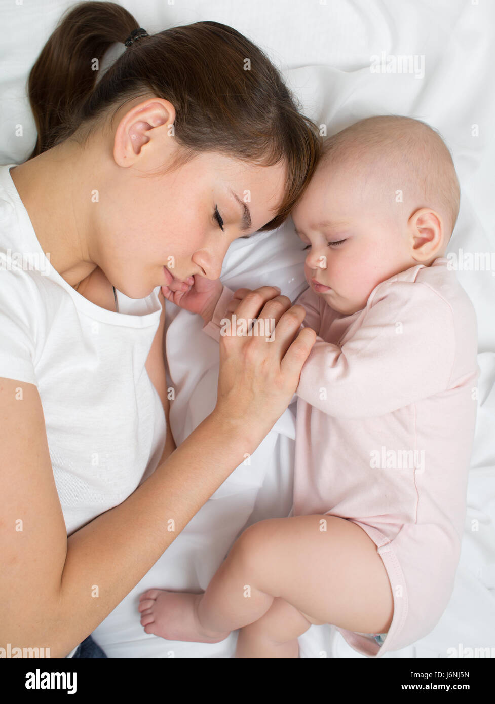 Maman avec bébé nouveau-né de dormir sur le lit à la maison. Vue de dessus, Close up. Banque D'Images