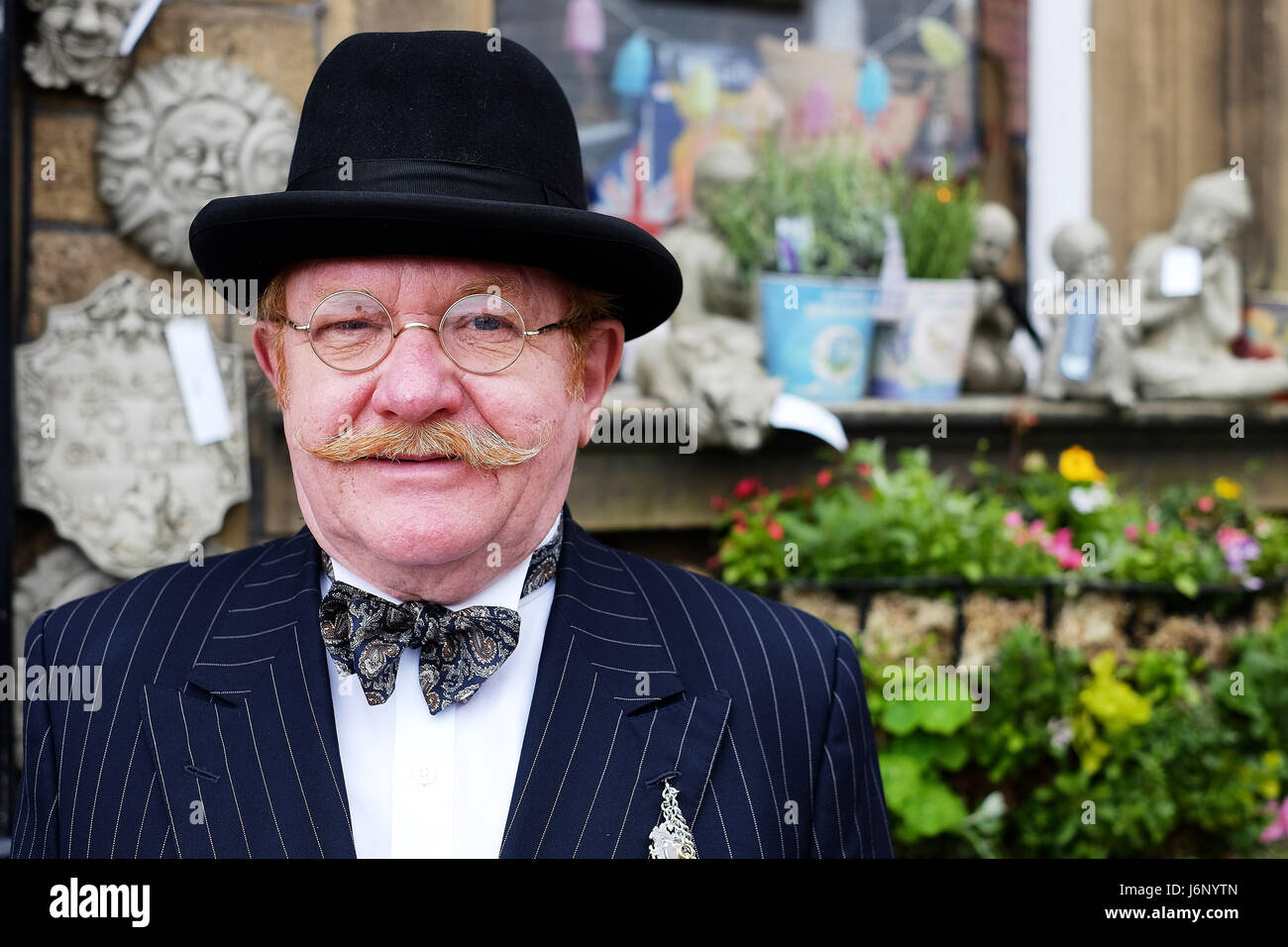 Un homme d'âge moyen en costume traditionnel avec une moustache et des lunettes rondes Banque D'Images