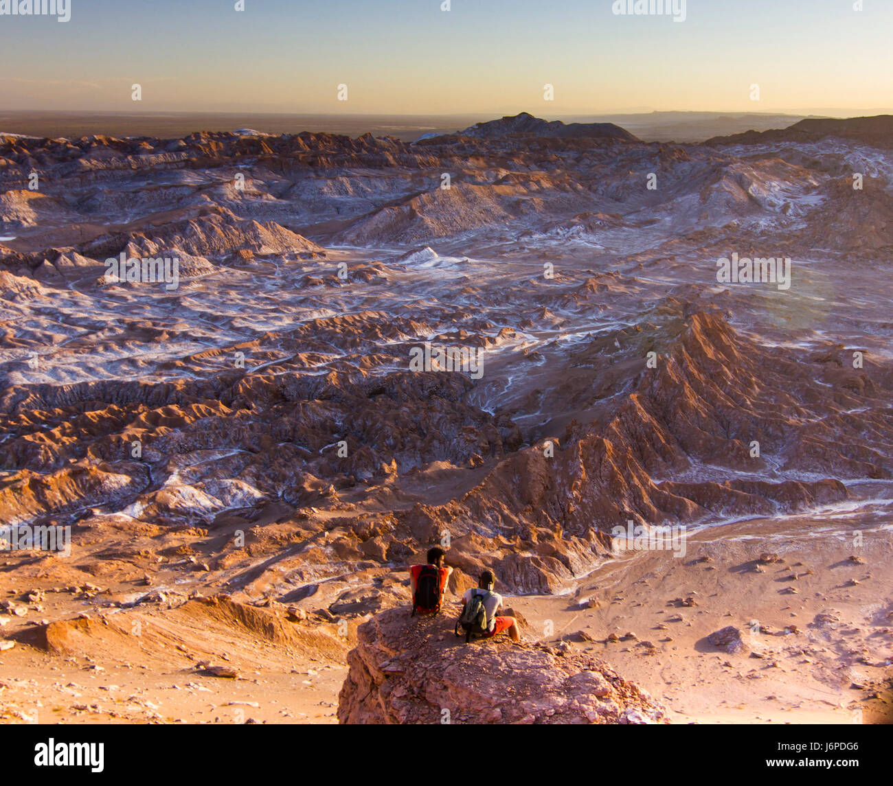 Homme assis sur une falaise dans la vallée de la Lune salée en désert d'Atacama au coucher du soleil Banque D'Images