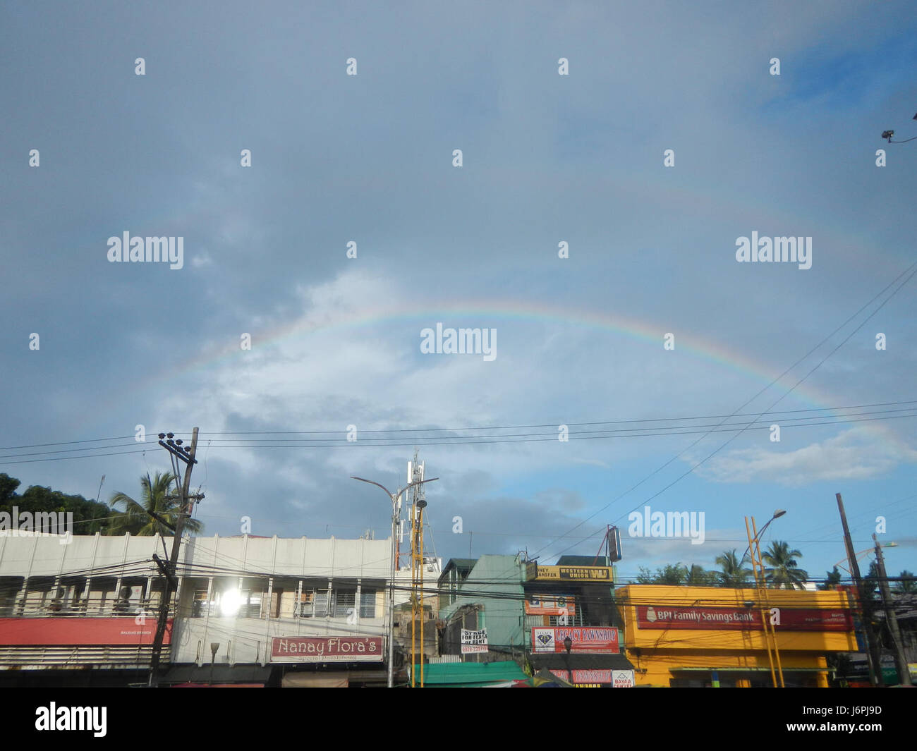 Cette image montre des arcs-en-ciel doubles capturés au-dessus de la ville proprement dite, de la tour de l'horloge de Glorietta et des environs à Baliuag, Bulacan. Le phénomène naturel rare des arcs-en-ciel doubles ajoute un élément visuel frappant à la scène. Banque D'Images