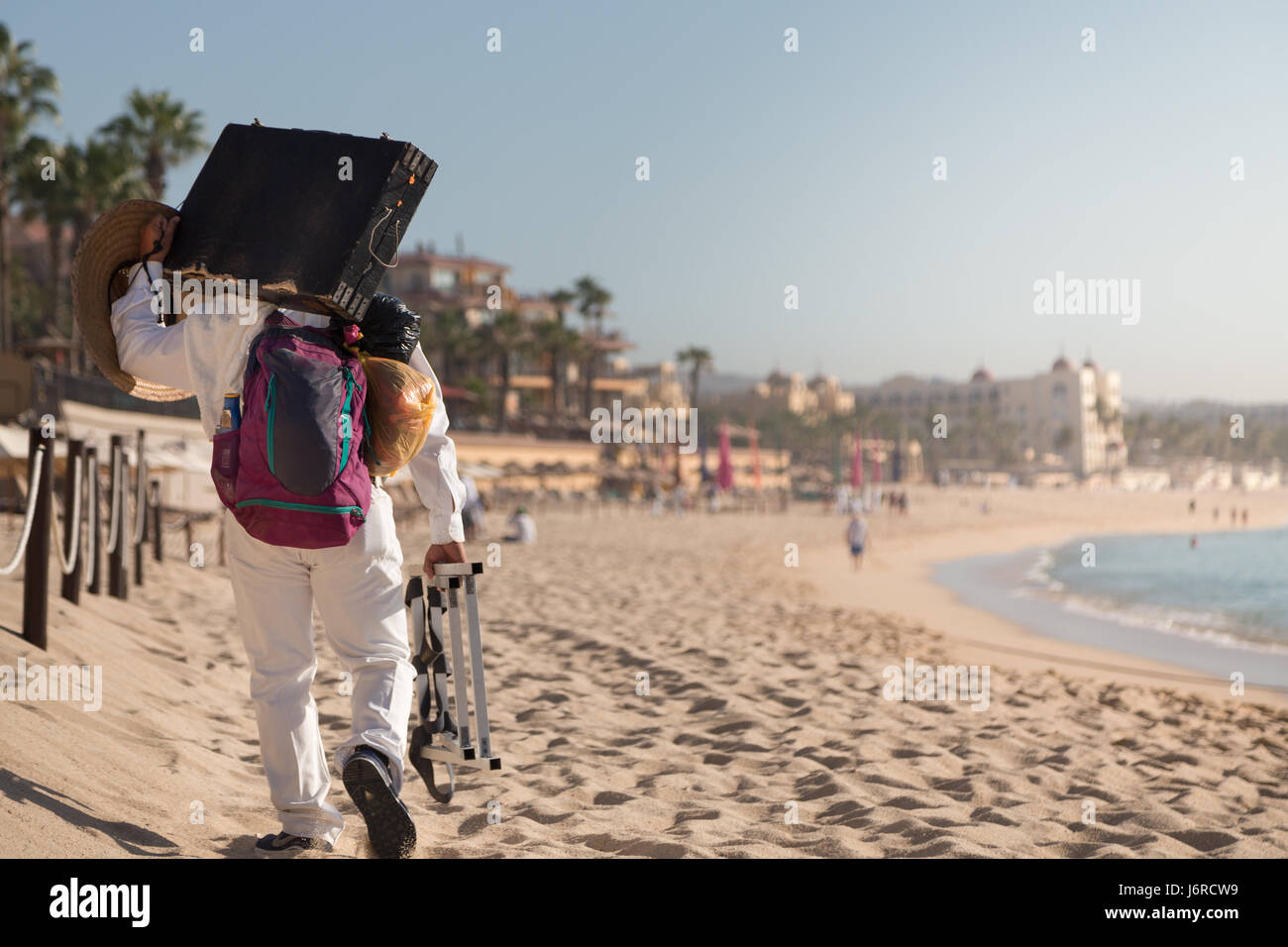 Un vendeur marchant sur la plage au Mexique à côté d'une station. Banque D'Images