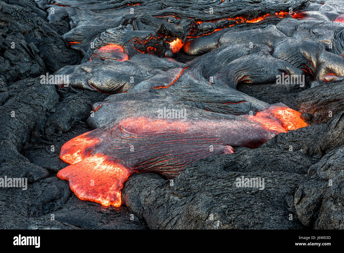 L'écoulement en surface de la lave s'échappe par les coins et recoins de la lave séchée pendant une éruption du volcan Kilauea. Banque D'Images