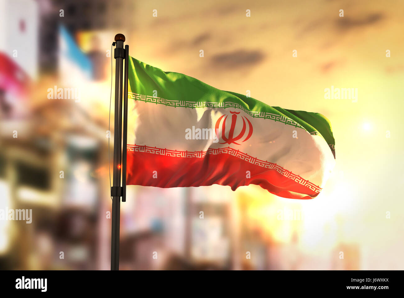 Drapeau de l'Iran contre ville fond flou rétroéclairage au lever du soleil Banque D'Images