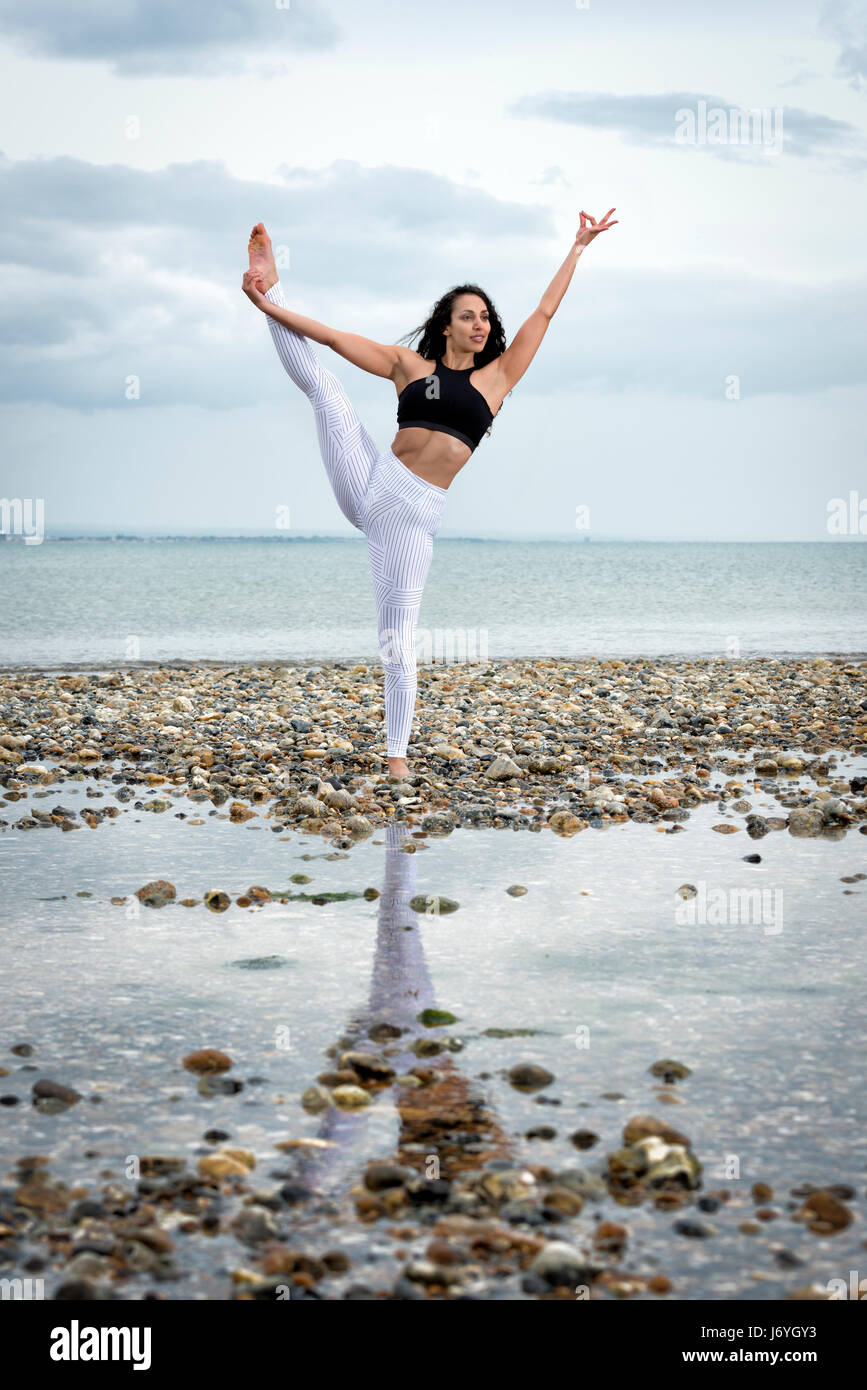 Woman practicing yoga par la mer Banque D'Images