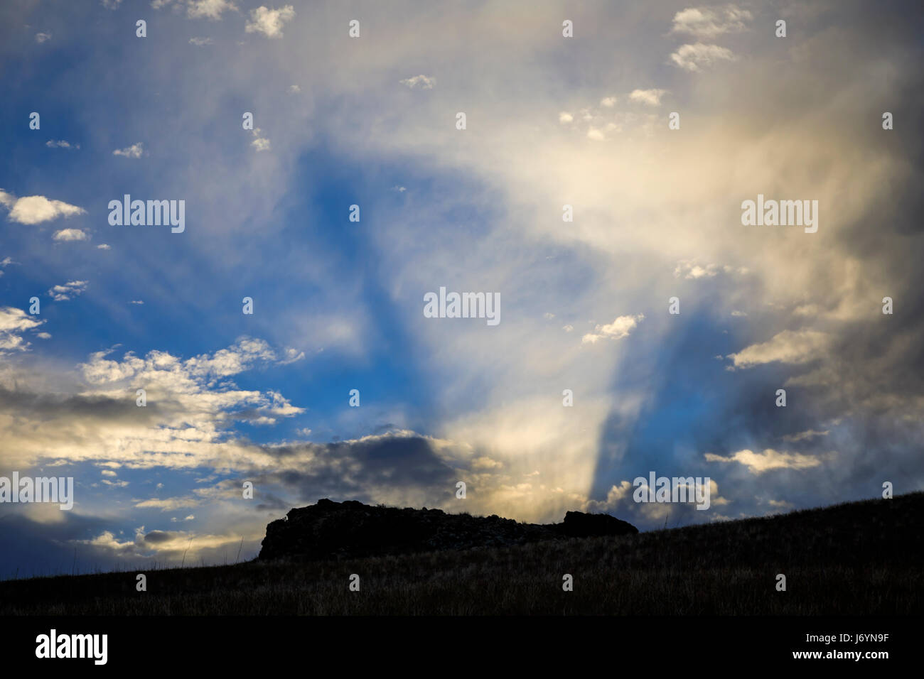 Dans cette photo, les rayons du soleil couchant illuminent le nuages sur une formation rocheuse sur une crête d'Antelope Island State Park, Utah, USA. Banque D'Images