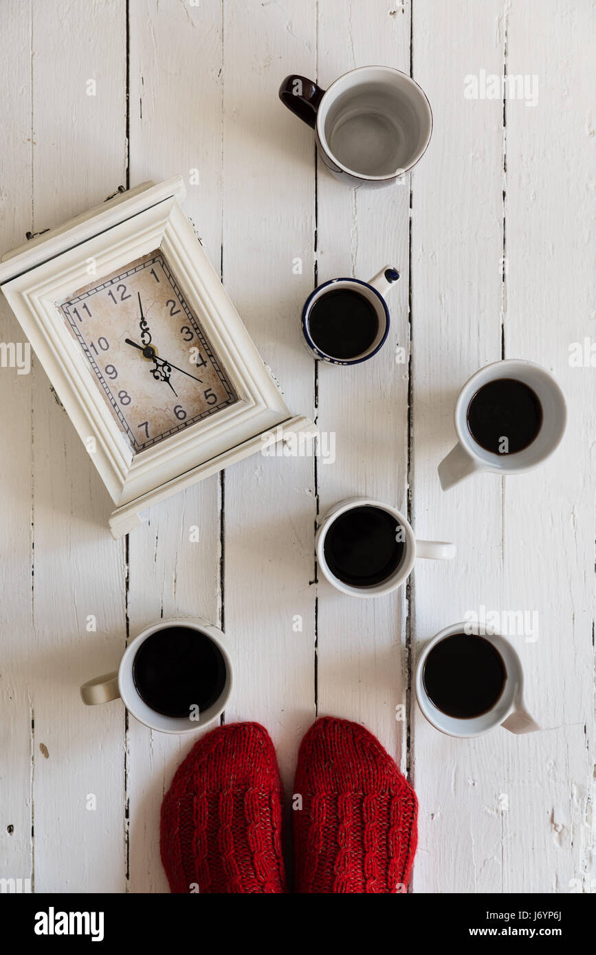 Pieds de femme debout près de l'horloge et tasses de café Banque D'Images