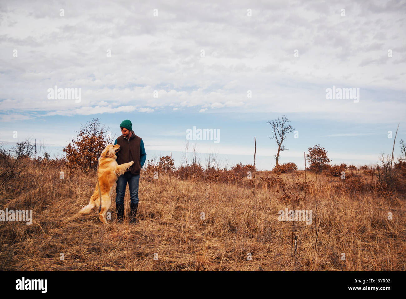 Homme debout dans un paysage rural avec golden retriever dog Banque D'Images