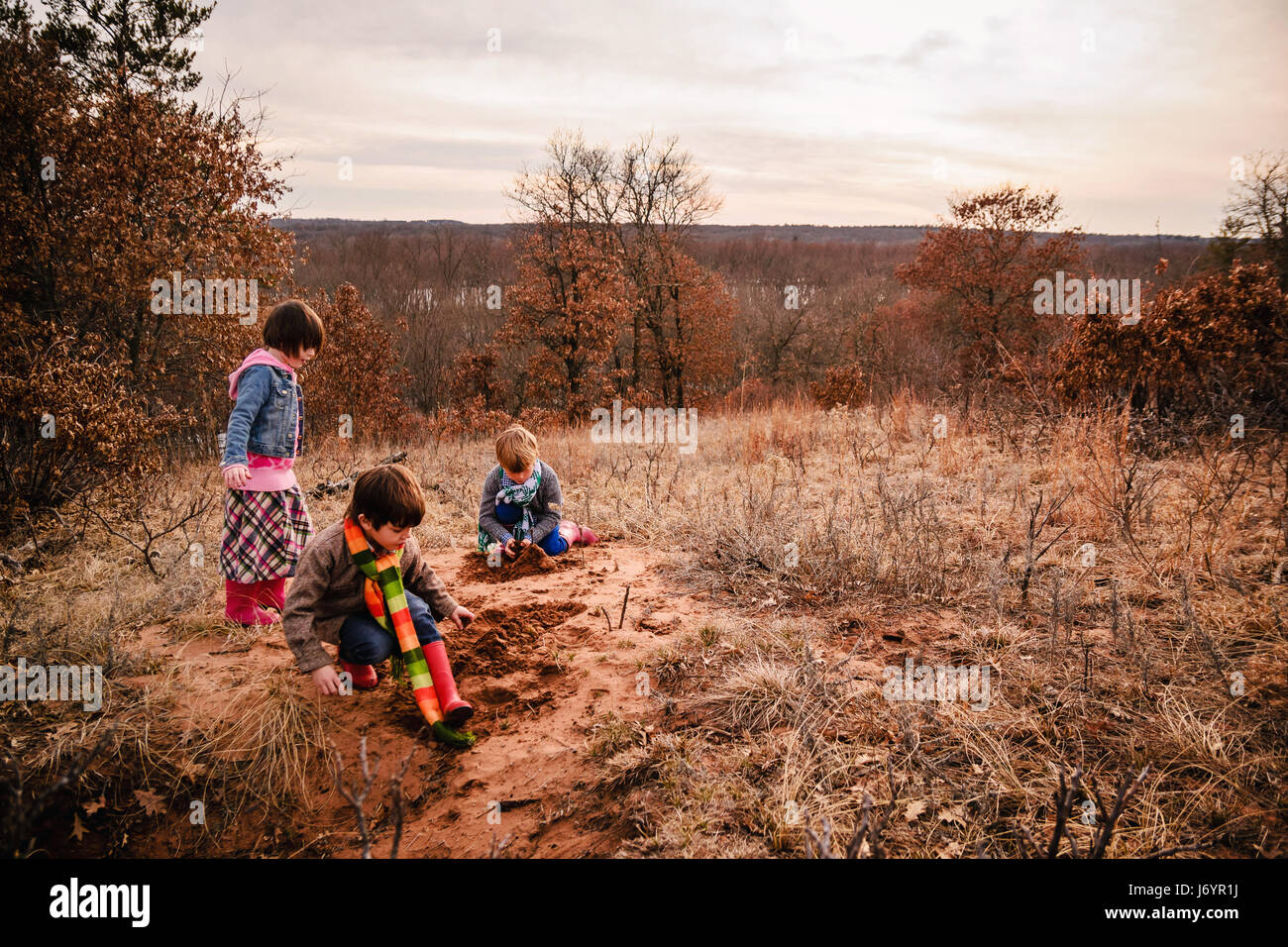 Deux garçons et une fille jouant dans un paysage rural Banque D'Images