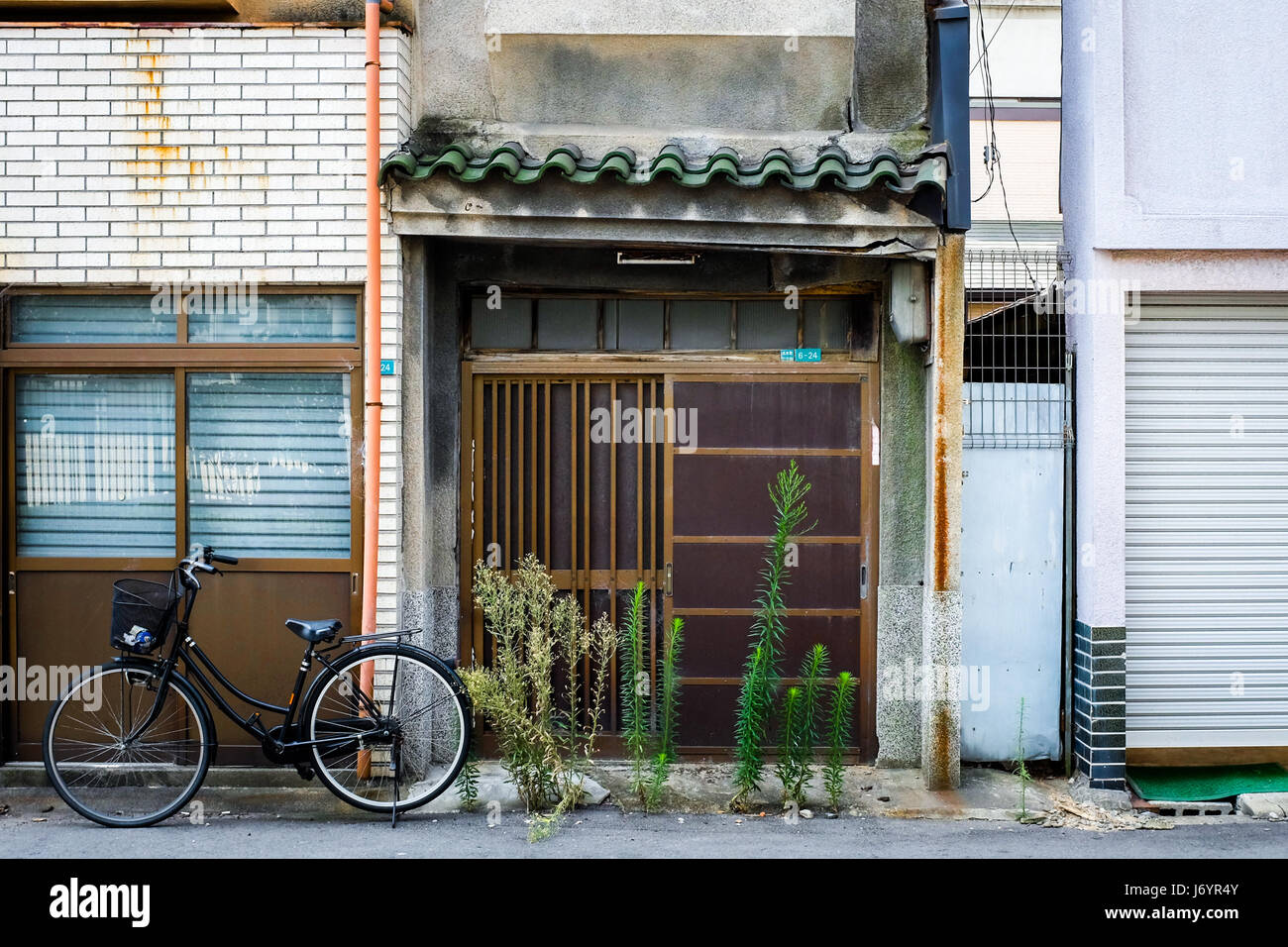 Une maison vide - sans doute - au Japon avec les plantes qui poussent en dehors de la porte. Banque D'Images