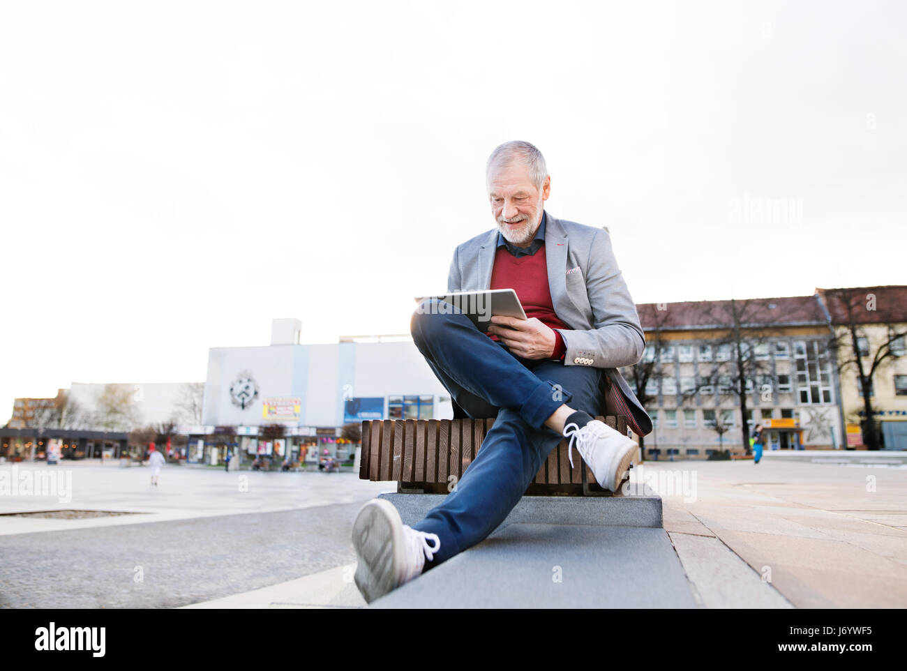 Senior man sitting on bench en ville, travaillant sur tablette Banque D'Images