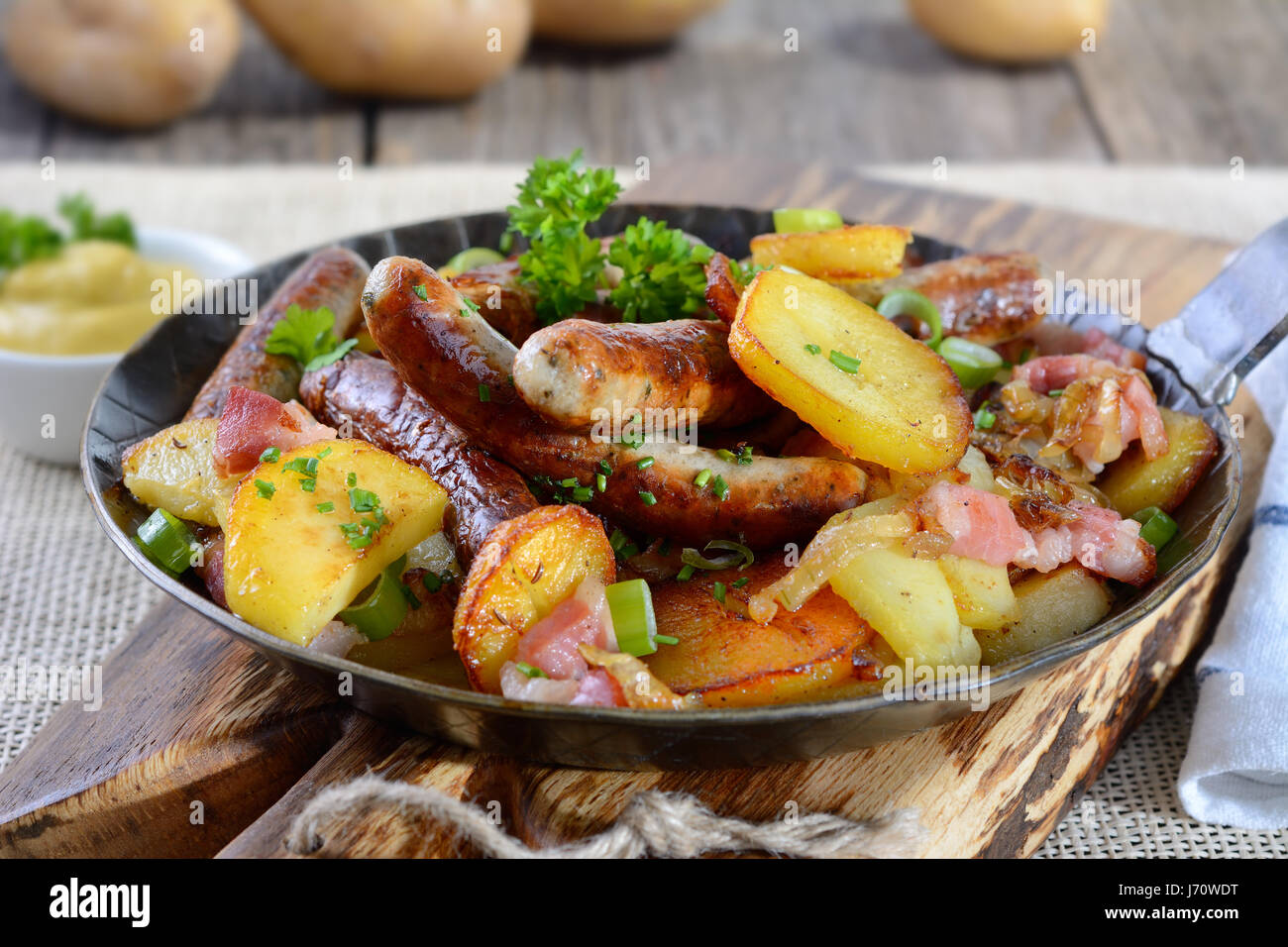Poêlée de saucisses de Nuremberg avec croustillant de pommes de terre et  bacon, servi dans une poêle de fer sur une planche en bois Photo Stock -  Alamy