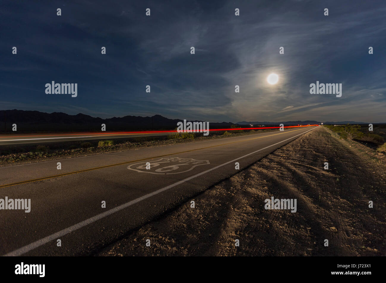 Signe de route 66 avec la pleine lune et de stries train dans le désert de Mojave en Californie. Banque D'Images