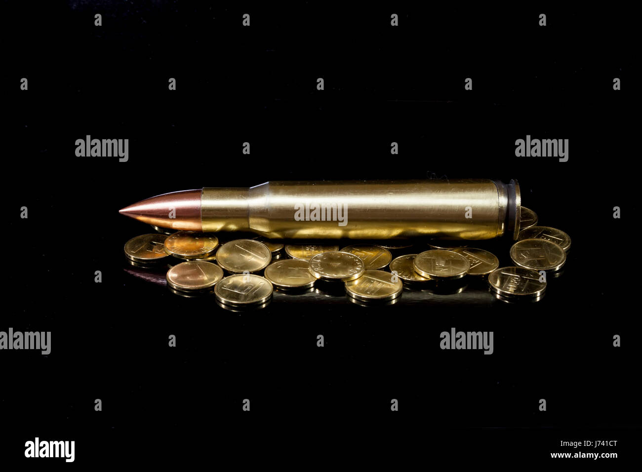 Balle de calibre élevé placé horizontalement et entouré par des pièces d'or brillant , image conceptuelle sur le coût de la guerre et les transactions d'armes Banque D'Images