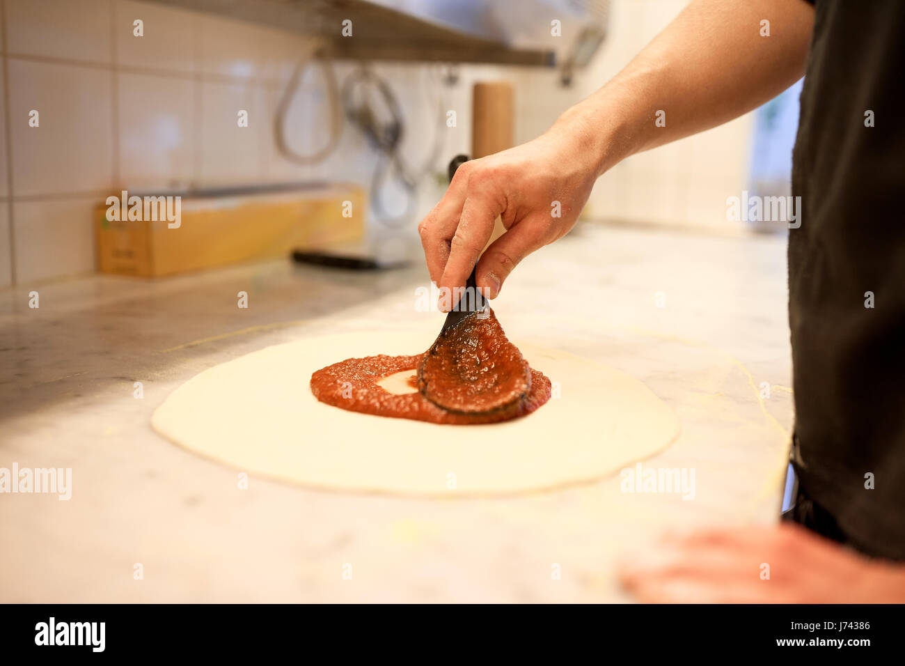 Faire cuire la sauce tomate à appliquer une pizza à la pizzeria Banque D'Images