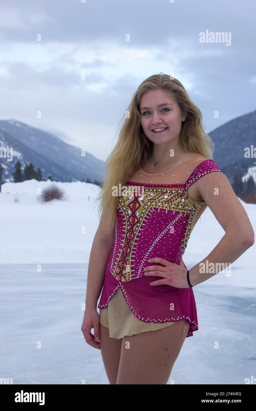 Un patineur artistique dans une robe rose et or pose sur un lac gelé Banque D'Images