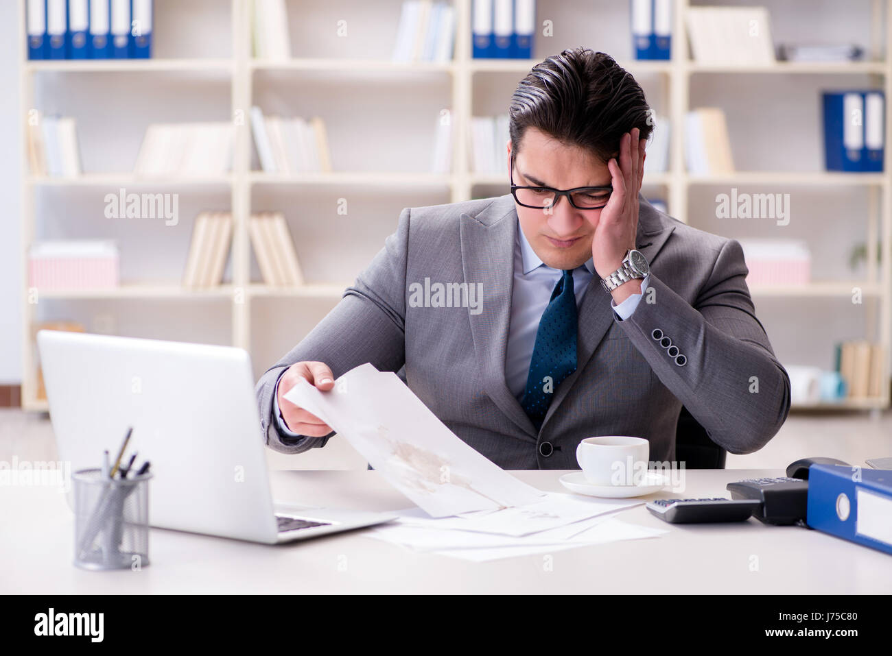 Businessman de renverser du café sur des documents importants Banque D'Images