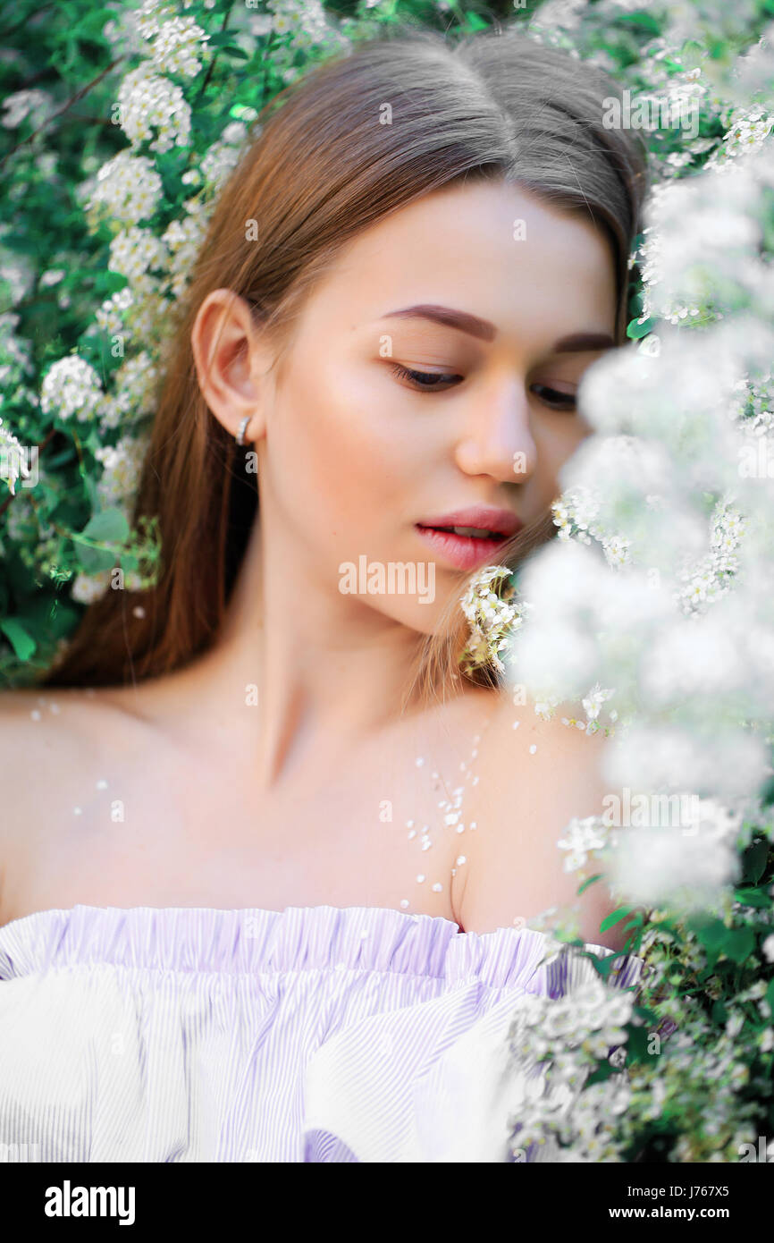 Une belle jeune fille se dresse parmi les arbres en fleurs. Fleurs blanches. Au printemps. Banque D'Images