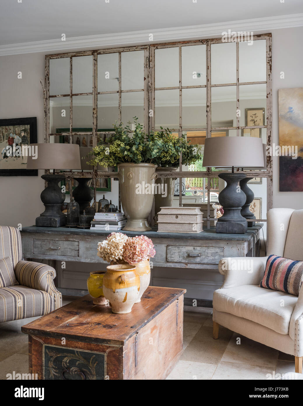 Paire de grandes lampes Tigné Tierlan gris sur de grandes table console en coin salon avec des fauteuils à dossier d'aile et commode ancienne. La peinture elle par sus Banque D'Images